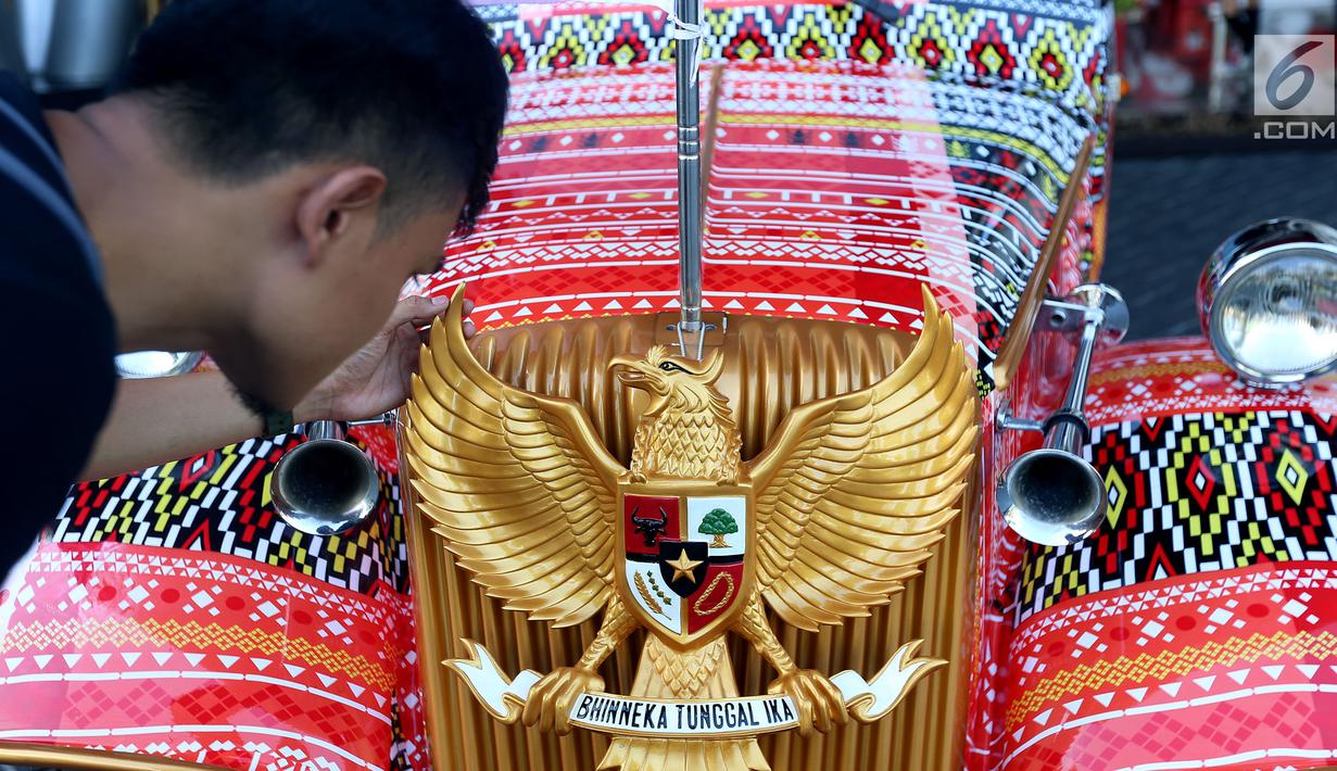 Seorang pria memegang burung Garuda Pancasila di mobil bercorak Ulos Mandailing yang akan digunakan acara ngunduh mantu Kahiyang-Bobby di Medan, Senin (20/11). (Liputan6.com/JohanTallo)