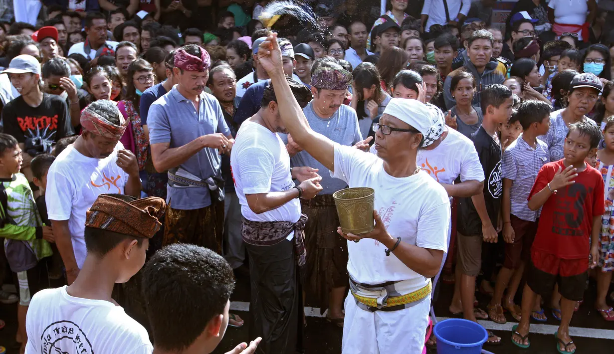 Seorang pemangku mencipratkan air pada peserta festival Omed-omedan di Bali, Kamis (29/3). Festival yang dilakukan sehari setelah Hari Raya Nyepi tersebut sekaligus untuk memohon keselamatan bagi warga setempat. (AP Photo/Firdia Lisnawati)