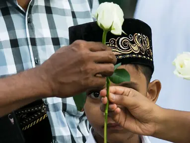 Umat Buddha Myanmar memberikan mawar putih kepada umat Islam yang akan melaksanakan salat Id pada perayaaan Idul Fitri di kota Than Lyin, pinggiran Yangon, Rabu (5/6/2019). Momen ini menjadi sebuah aksi solidaritas yang langka di sebuah negara, di mana Islam kerap difitnah.  (Sai Aung MAIN/AFP)