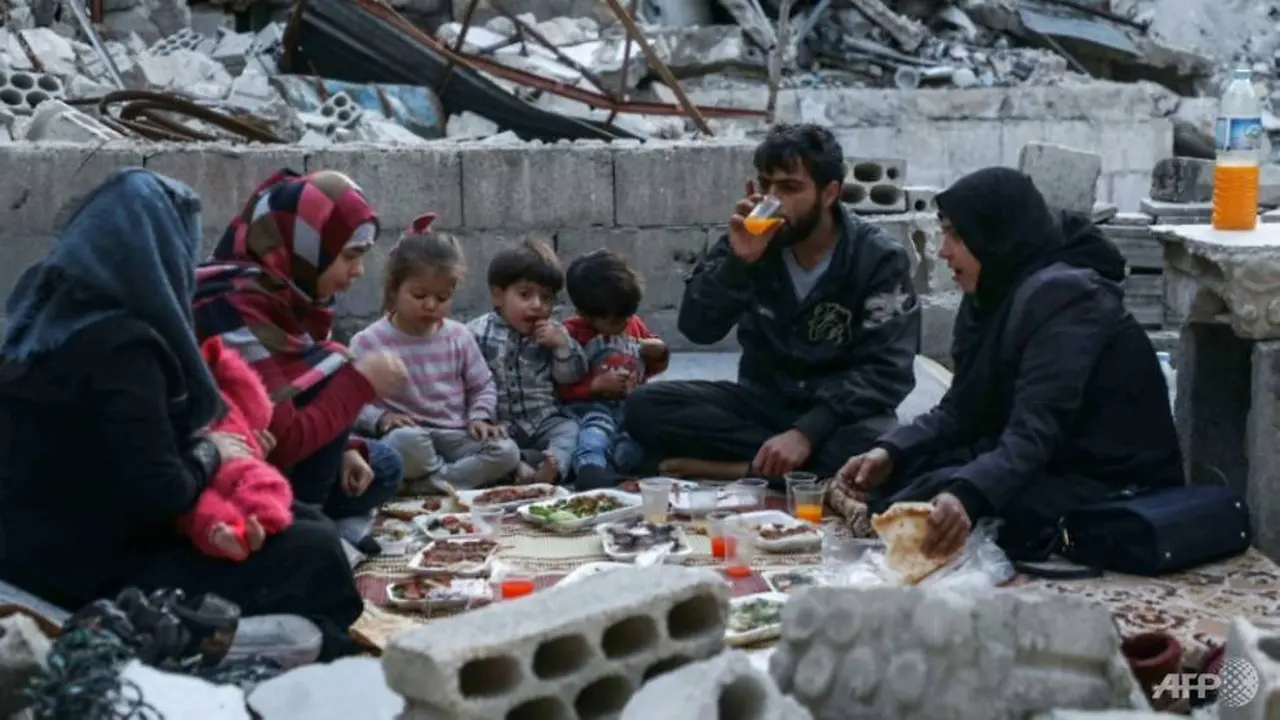 Sebuah keluarga di Idlib, Suriah berbuka puasa di tengah puing-puing sisa rumah mereka yang hancur.