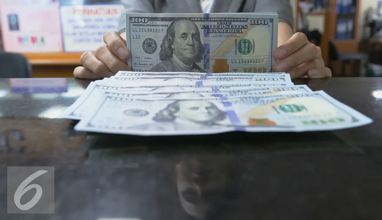 Petugas menunjukkan Dolar AS di toko penukaran uang di Jakarta, Selasa (7/6). Langkah wait and see para pelaku bisnis menambah tekanan terhadap dollar AS. Mata uang dollar AS terhadap rupiah dibuka Rp13.361. (Liputan6.com/Angga Yuniar)