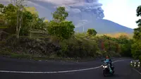 Warga mengendarai motor saat Gunung Agung Mengeluarkan abu vulkanik di Kecamatan Kubu, Karangasem, Bali, Minggu (26/11). Semburan asap dan abu vulkanik Gunung Agung mencapai ketinggian 1.500 meter dari puncak Gunung Agung. (AFP/Sonny Tumbelaka)