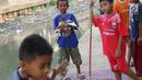 Seorang anak memegang burung dara di bantaran anak Sungai Ciliwung, Jakarta, Rabu (6/6). Meskipun tidak layak sebagai tempat bermain, namun lokasi itu menjadi tempat bagi anak-anak untuk menunggu waktu berbuka. (Liputan6.com/Immanuel Antonius)