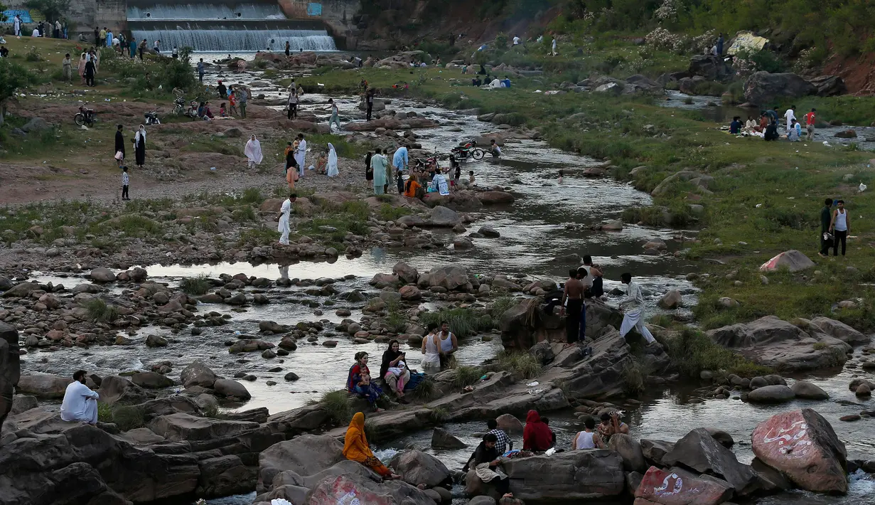Orang-orang berkumpul di sungai untuk mendinginkan diri ketika suhu mencapai 40 derajat celsius di Islamabad, Pakistan pada Rabu (27/5/2020). Banyak kota di Pakistan menghadapi kondisi gelombang panas dengan suhu mencapai 50 derajat celsius di beberapa tempat.  (AP Photo/Anjum Naveed)