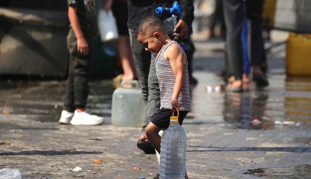 Seorang anak laki-laki Palestina membawa botol plastik besar berisi air di sebuah kamp pengungsi Nuseirat, yang terletak di Jalur Gaza tengah, pada 2 November 2025. Juru bicara Dana Anak-anak (UNICEF) Perserikatan Bangsa Bangsa (PBB), Tess Ingram mengungkap ada lebih dari satu juta anak di Jalur Gaza masih membutuhkan air bersih dan makanan. (EYAD BABA/AFP)