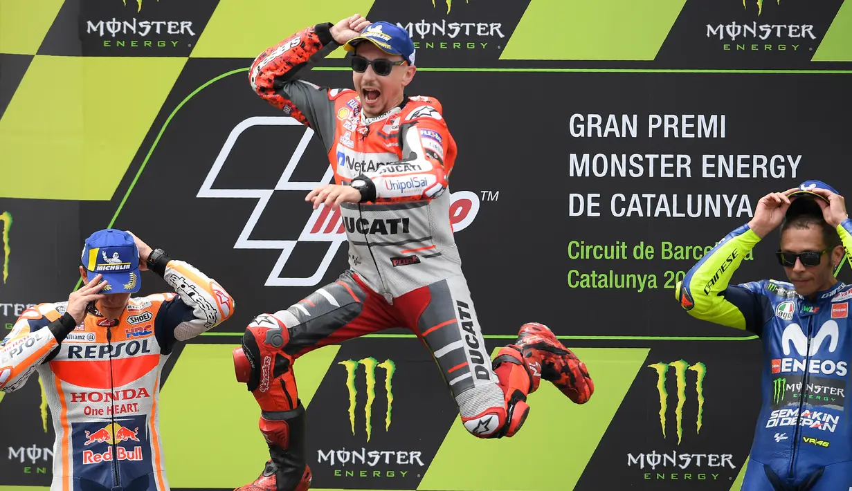 Pembalap Spanyol, Jorge Lorenzo (tengah) melompat merayakan selebrasi didampingi posisi kedua pembalap Marc Marquez dan posisi ketiga Valentino Rossi usai balapan MotoGP Catalunya di Sirkuit Catalunya, Montmelo, (17/6). (AFP PHOTO / Lluis Gen)