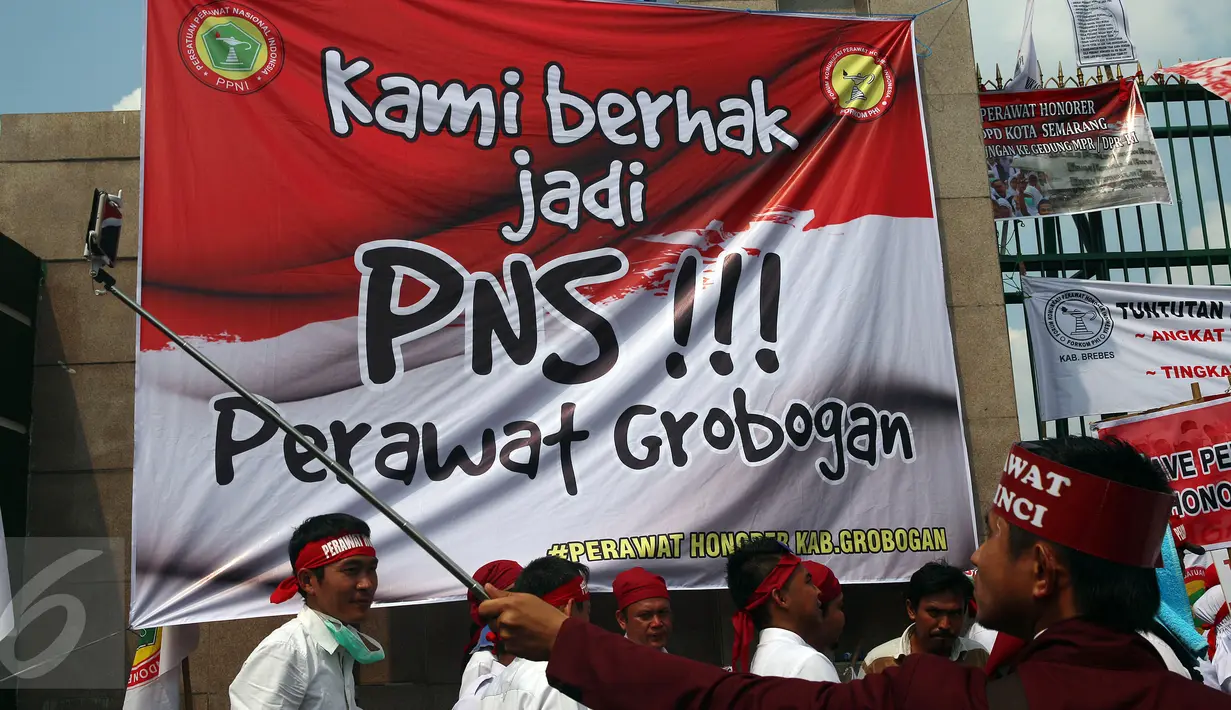 Seorang peserta aksi berselfie saat mengikuti unjuk rasa di depan Gedung DPR, Jakarta, Kamis (16/3). Mereka ingin pemerintah segera mengangkat status mereka dari pegawai honorer menjadi Pegawai Negeri Sipil (PNS). (Liputan6.com/Johan Tallo)