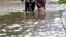 Pengendara mendorong sepeda motornya melewati banjir yang menggenangi kawasan Jalan Wolter Monginsidi Jakarta dan sekitarnya, Sabtu (20/2/2021). Hujan yang mengguyur Jakarta sejak Jumat (19/2) membuat sejumlah titik di Jakarta terendam banjir. (Liputan6.com/Helmi Fithriansyah)