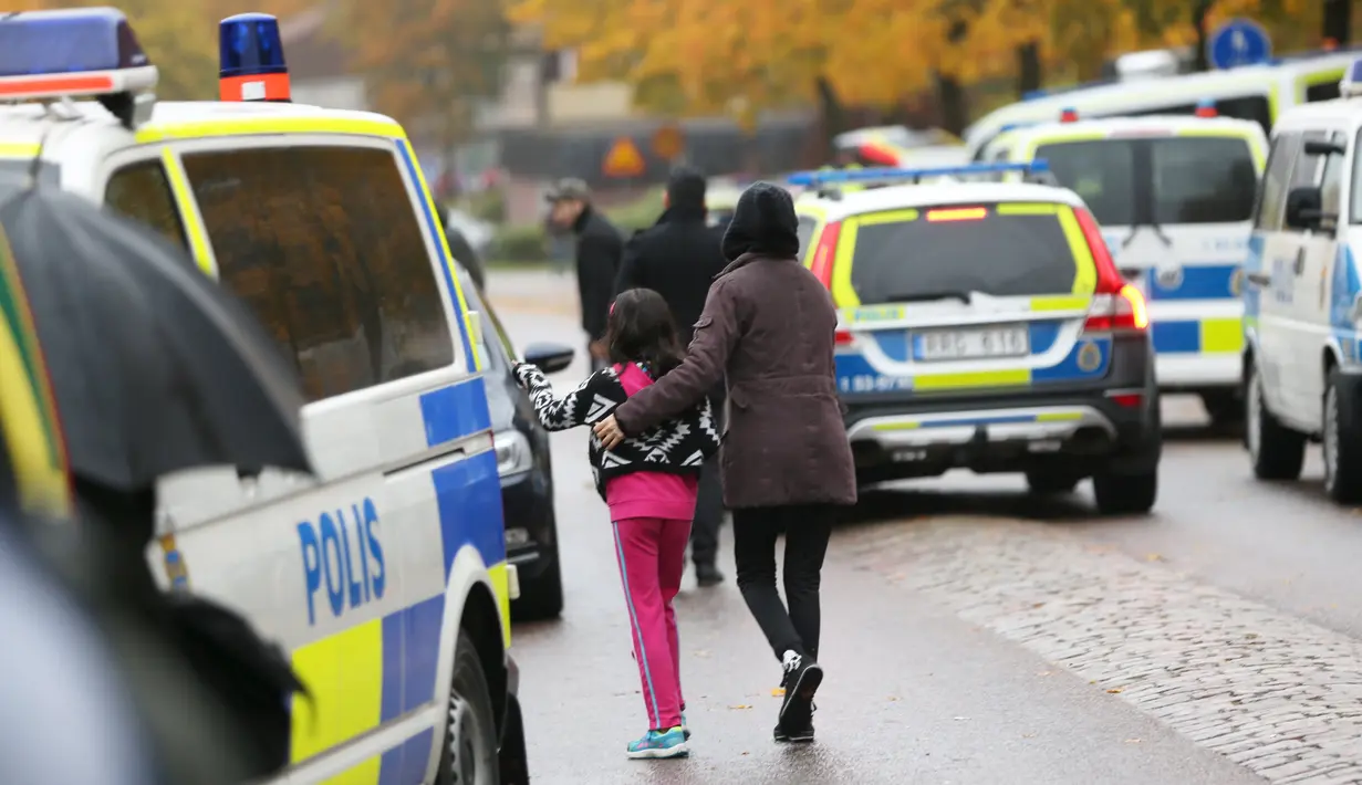 Seorang murid dan orangtuanya meninggalkan sekolah Kronan di Trollhattan, Swedia barat, Kamis (22/10). Pria bertopeng dan bersenjatakan pedang menyerang sekolah tersebut dan menewaskan seorang murid dan guru. (REUTERS/Bjorn Larsson Rosvall/TT News Agency)