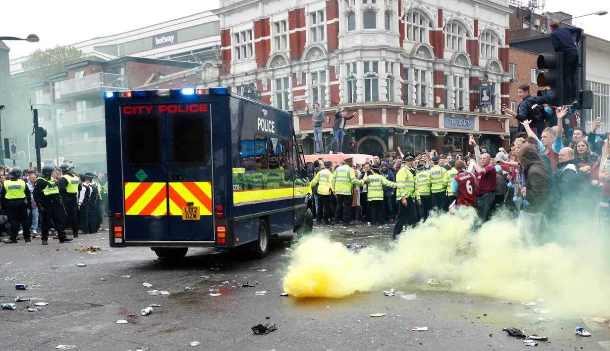 Petugas kepolisian menembakan bom asap saat suporter West Ham United menyerang bus skuat Manchester United di Upton Park,  London, Selasa (10/5). Kedatangan bus MU disambut dengan lemparan botol dari suporter fans West Ham. (Reuters/Eddie Keogh)
