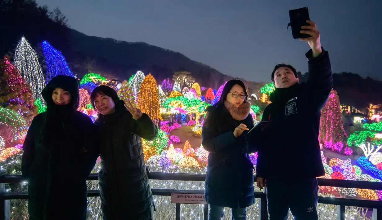 Gambar pada 11 Januari 2020, pengunjung berswafoto saat menyaksikan keindahan ribuan lampu di Garden of Morning Calm, sebelah timur Seoul di distrik Gapyeong, Korea Selatan. Festival cahaya tahunan tersebut dinikmati saat musim dingin, Desember sampai akhir bulan Maret. (Ed JONES / AFP)