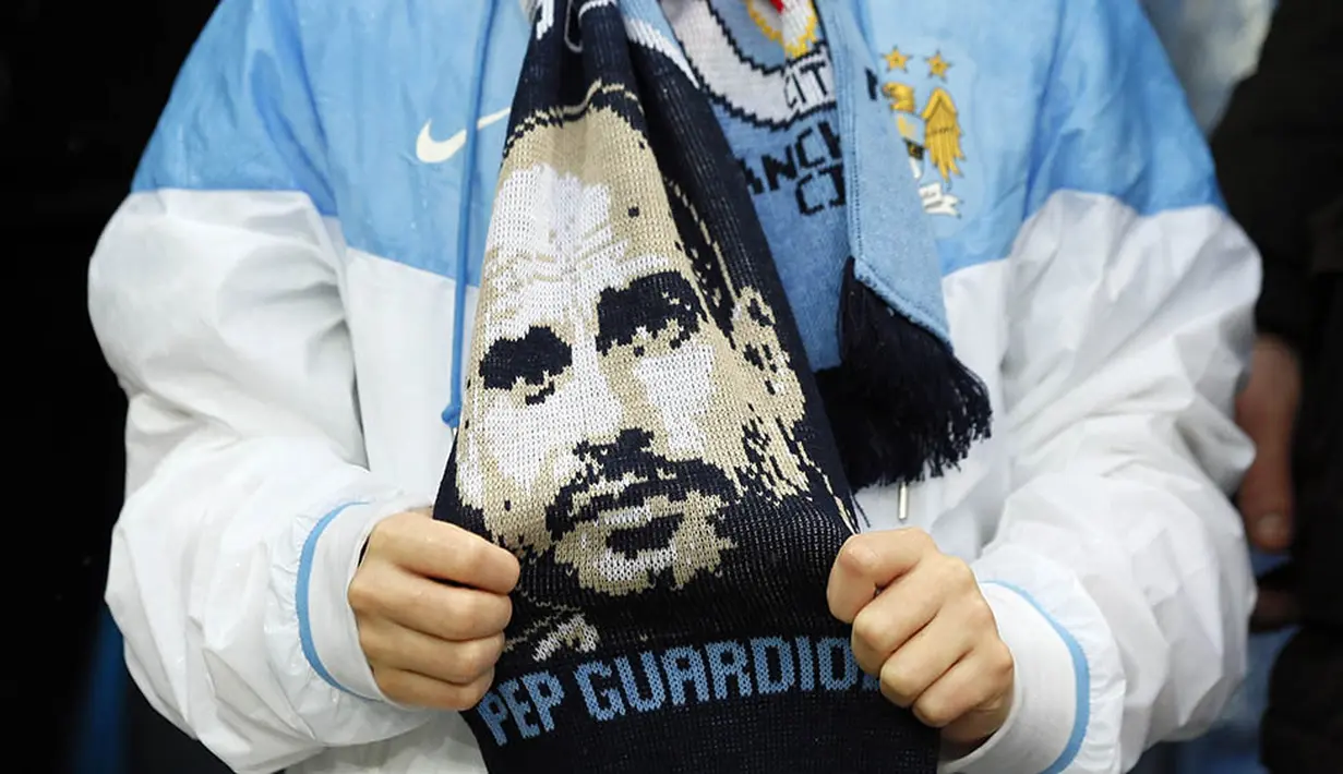 Fans memakai syal bergambar pelatih Manchester City musim depan, Josep Guardiola, saat laga melawan Leicester di Stadion Ettihad, Inggris, Sabtu (6/2/2016). City Takluik 1-3 dari Leicester. (Reuters/Jason Cairnduff)