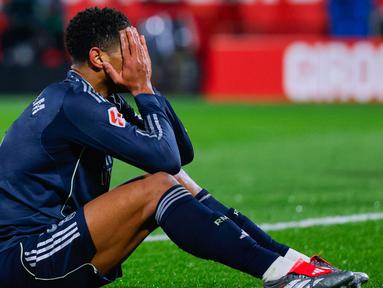 Pemain Real Madrid, Jude Bellingham, menutup wajahnya lantaran kecewa setelah bermain imbang 1-1 ketika menghadapi tuan rumah Girona pada laga lanjutan La Liga 2025/2026 di Montilivi, Senin (1/12/2025) dini hari WIB. (AP Photo/Joan Monfort)