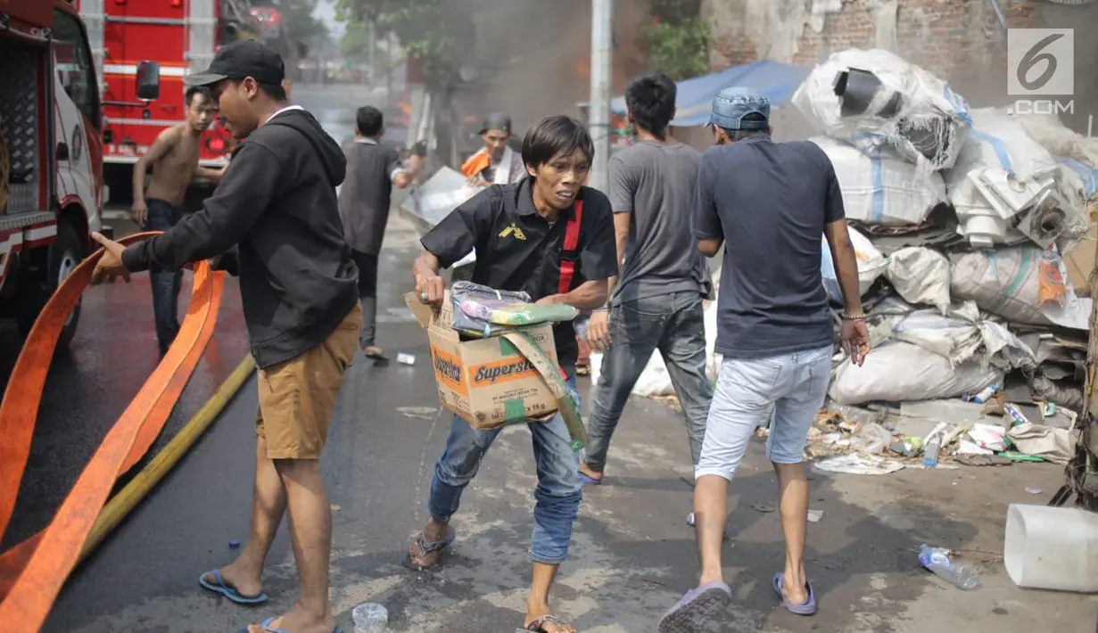 Warga berusaha menyelamatkan barang-barang saat api melalap gudang di Jalan Kampung Bandan, Ancol, Jakarta Utara, Kamis (5/7). (Liputan6.com/Faizal Fanani)