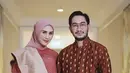 Baju kurung yang dibuat oleh Didiet Maulana dipadukan selendang dan bawahan kain songket warna coral. Jeje sang suami mengenakan atasan lengan panjang coklat bermotif. [@syahnazs]