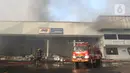 Petugas memadamkan api saat terjadi kebakaran di Gudang JNE Express, Jalan Pekapuran Raya, Depok, pada Senin (12/9/2022). Api pertama kali diketahui oleh salah satu sekuriti yang bertugas sekitar pukul 03.45 WIB. (Liputan6.com/Herman Zakharia)
