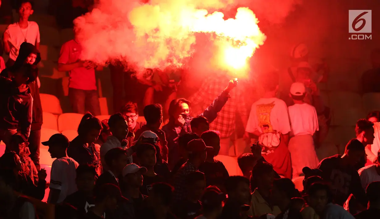 Suporter tim Garuda menyalakan suar saat menyaksikan kemenangan Timnas Indonesia U-16  atas Singapura U-16 di laga persahabatan di Stadion Wibawa Mukti, Kab Bekasi, Kamis (8/6). Indonesia U-16 menang telak 4-0. (Liputan6.com/Helmi Fithriansyah)