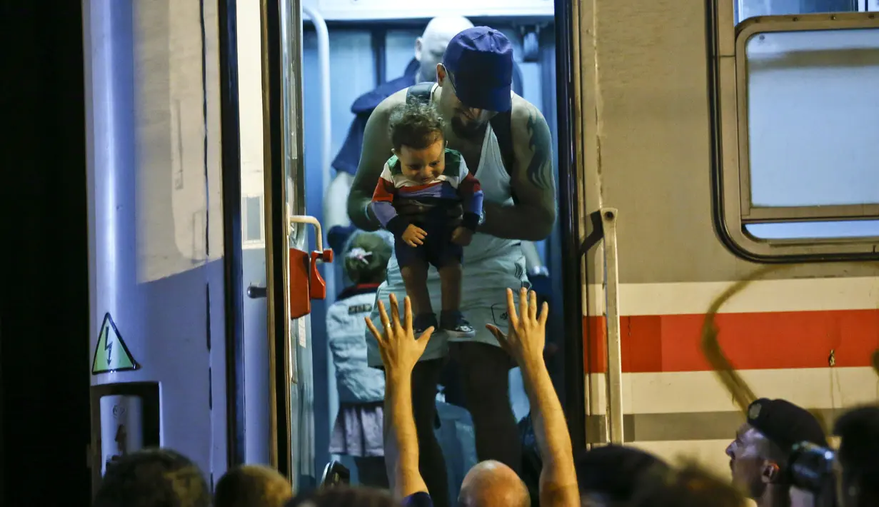 Seorang anak dinaikkan ke dalam kereta api saat terjadi pengungsian besar-besaran di sebuah stasiun kereta api di Tovarnik (19/9/2015). (REUTERS / Antonio)