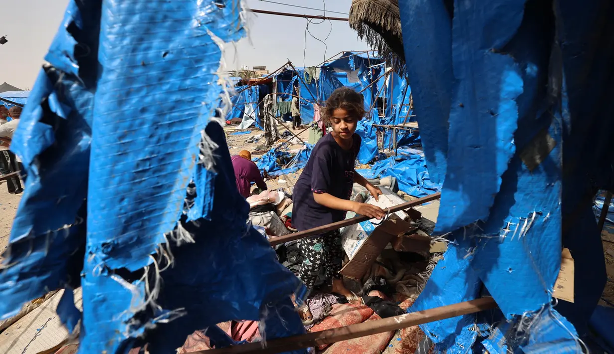 Seorang anak memeriksa kerusakan tenda-tenda untuk warga Gaza yang mengungsi di luar rumah sakit Martir Al-Aqsa, Deir el-Balah, Jalur Gaza Tengah, setelah serangan udara Israel semalam yang dilaporkan menghantam, pada 17 Mei 2025. (Eyad BABA/AFP)