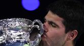Carlos Alcaraz mencium piala usai berhasil menjuarai Australian Open 2026 setelah menaklukkan Novak Djokovic dalam laga sengit yang dilangsungkan di Melbourne Park pada (1/2/2026) sore WIB. (AFP/Martin Keep)