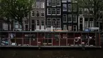 Pejalan kaki melintas dekat Catboat, tempat penampungan berbentuk kapal yang terapung di Amsterdam, Belanda, 3 Agustus 2017. Catboat sangat terkenal sebagai tempat perlindungan untuk para kucing jalanan yang terlantar. (AP Photo/Muhammed Muheisen)