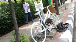 Pejalan kaki melintasi monumen sepeda putih atau ghost bike di sebuah tiang kawasan Jenderal Gatot Subroto, Jakarta, Senin (12/3). Monumen itu untuk mengenang pesepeda Raden Sandy Syafiek yang tewas tertabrak mobil. (Liputan6.com/Immanuel Antonius)