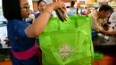 Karyawan mengemas barang belanjaan konsumen dengan tas belanja nonplastik di sebuah supermarket di Denpasar, 16 Juli 2019. Bali menerapkan pelarangan penggunaan plastik sekali pakai yang tertuang dalam Peraturan Gubernur (Pergub) Nomor 97 Tahun 2018. (SONNY TUMBELAKA/AFP)