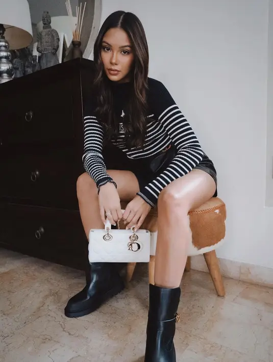 Model Indonesia Alyssa Daguise tampil kasual dengan  long sleeved sweater Dior, dipadu leather short pants dan Dior Small Lady D-Joy warna putih. [Dior].