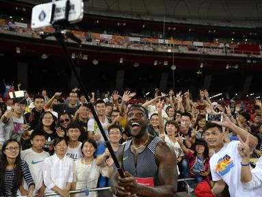 Pelari asal Amerika Serikat, Justin Gatlin berfoto selfie bersama ratusan fans usai lari menjuarai 100m putra pada kejuaraan IAAF World Challenge di National Olympic Stadium atau 'Birds Nest', Beijing, (18/5/2016). (AFP/Wang Zhao)