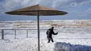 Seorang pria menggunakan foto cerdasnya untuk menangkap buih laut yang menutupi sebagian trotoar di pelabuhan Tel Aviv di Laut Mediterania, Israel, Selasa, 7 Februari 2023, saat angin kencang dan gelombang dari Badai Barbara menghantam negara itu. Ini bukan salju, tapi buih dari Mediterania. (AP Photo/Ariel Schalit)