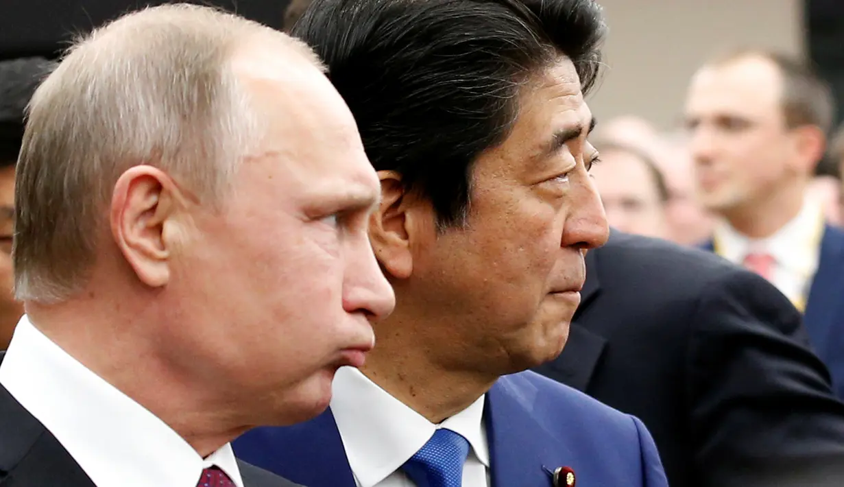 Presiden Rusia Vladimir Putin (kiri) dan Perdana Menteri Jepang Shinzo Abe tiba di tempat pertemuan dialog bisnis Jepang-Rusia di Tokyo, Jepang, Jumat (16/12). (REUTERS / Kim Kyung-Hoon)