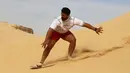 Ekspresi sorang pria saat berseluncur menggunakan papan sandboards di gurun pasir Wadi el-Rayan Fayoum, Mesir (18/11). Peralatan yang dibutuhkan dalam olahraga ini yaitu sebuah papan luncur. (Reuters/Mohamed Abd El Ghany)