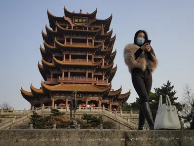 Seorang perempuan bermasker mengunjungi Menara Bangau Kuning yang ikonik di Wuhan di provinsi Hubei, China, Jumat (15/1/2021). Selain masker, orang-orang menjalani kehidupan sehari-hari mereka seperti sebelumnya di Wuhan, tempat pertama kali virus corona COVID-19 terdeteksi. (AP Photo/Ng Han Guan)