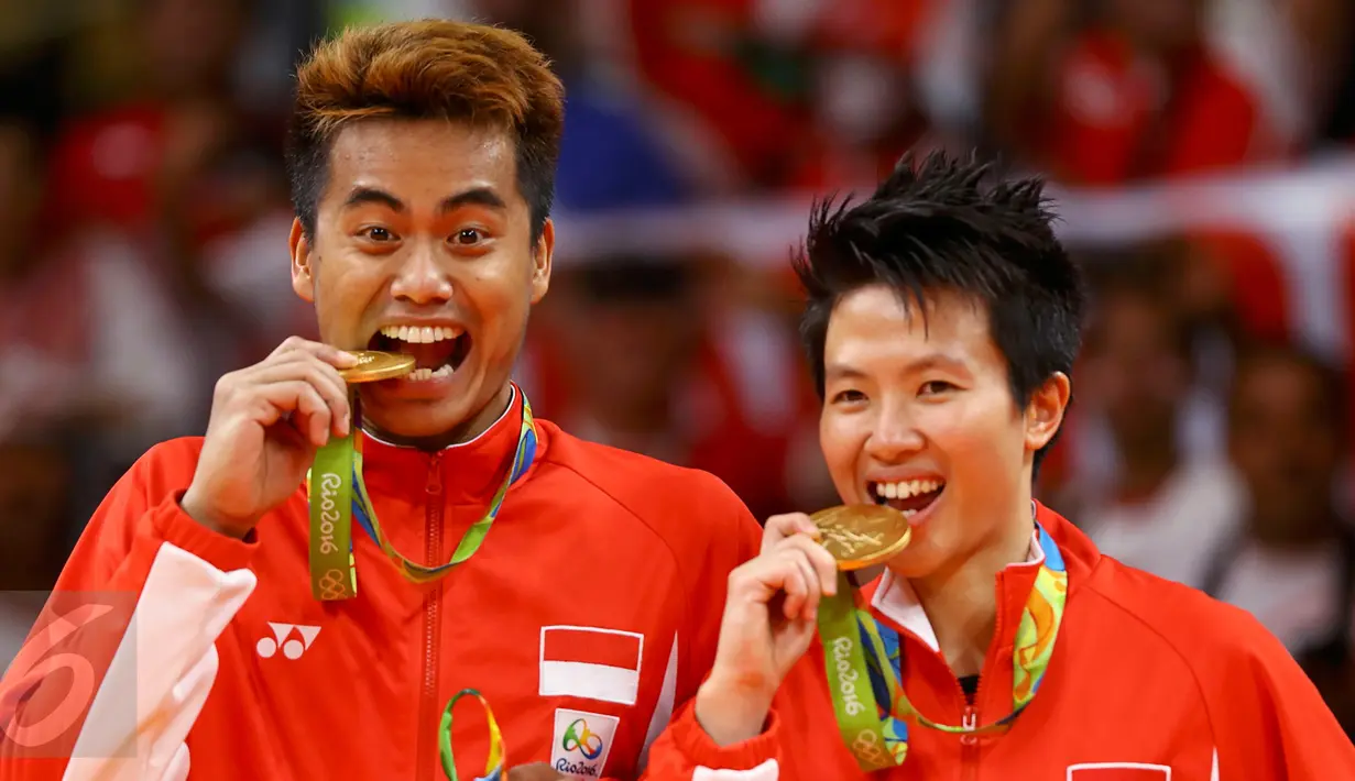 Pasangan ganda campuran Indonesia, Tontowi Ahmad dan Liliyana Natsir mengigit medali emas usai mengalahkan lawannya asal Malaysia Peng Soon Chan dan Liu Ying Goh pada final bulutangkis di Riocentro Pavilion 4 , Brasil. (REUTERS/Mike Blake)