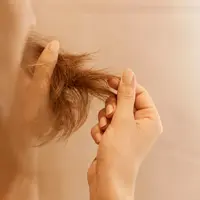 Close up seorang perempuan yang sedang memegang ujung rambutnya yang rusak (Foto Dok: Freepik/user18526052).