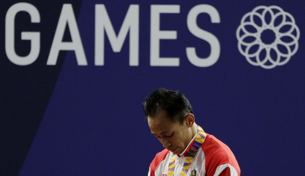 Lifter Suratman tertunduk saat naik podium usai mendapatkan medali perunggu SEA Games 2019 cabang angkat besi nomor 55 kg di Stadion Rizal Memorial, Manila, Minggu (1/12). Dirinya meraih perak dengan total angkatan 250 kg. (Bola.com/M Iqbal Ichsan)