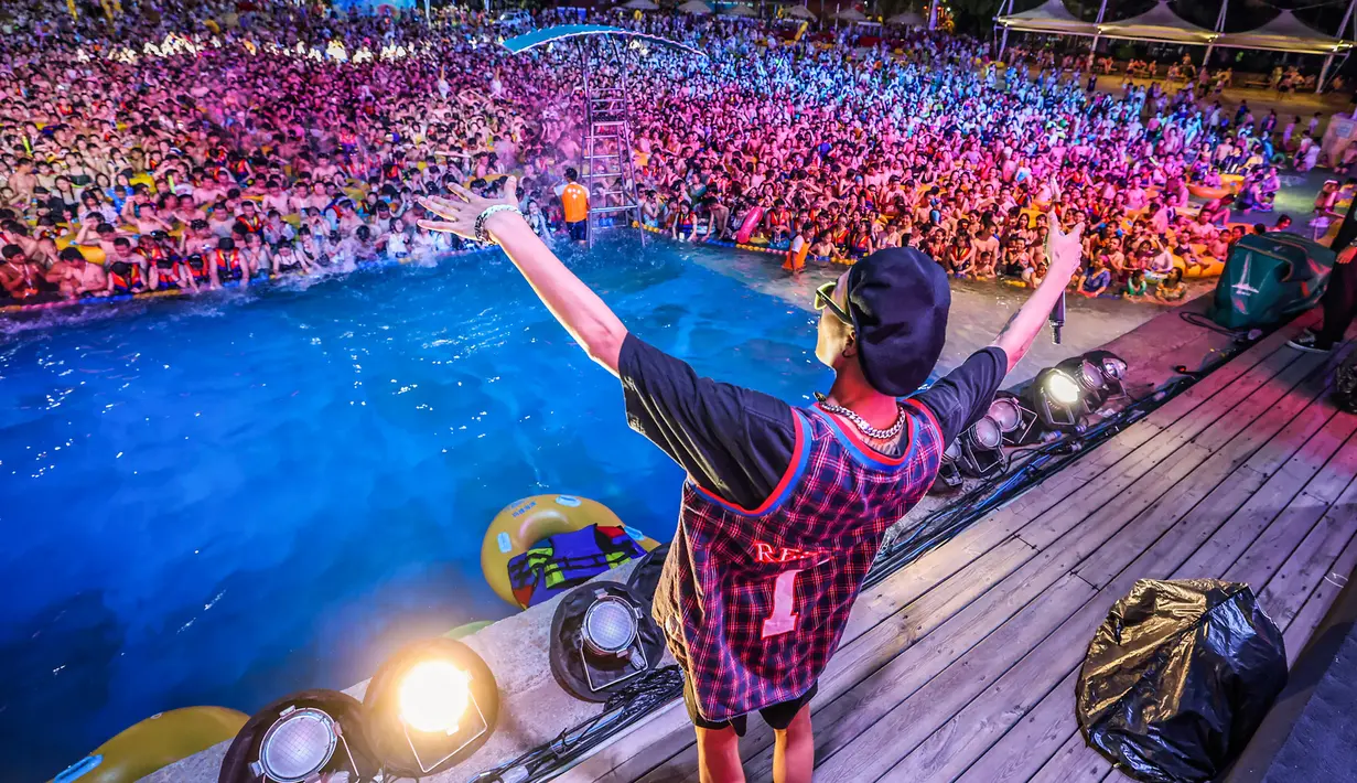 Orang-orang menonton pertunjukan musik sambil bermain air di sebuah taman air atau water park di Wuhan, provinsi Hubei, China pada 15 Agustus 2020. Taman air itu dibuka lagi pada Juni setelah Wuhan mengurangi peraturan ketat karantina yang sudah berjalan selama 76 hari. (STR/AFP)