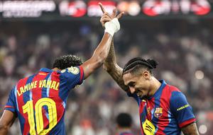 Lamine Yamal (kiri) dan Raphinha (kanan) melakukan selebrasi merayakan sukses meraih gelar Piala Super Spanyol seusai menaklukkan Real Madrid, Senin (12/1/2026) dini hari WIB. (Fadel SENNA / AFP)