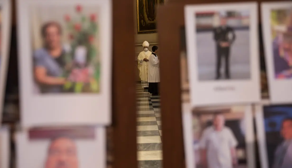 Seorang pendeta berdiri di antara potret korban meninggal akibat virus corona di dalam Katedral, di Lima, Peru, Minggu (14/6/2020). Misa Minggu di Katedral Lima dihadiri lebih dari 4.000 potret mereka yang telah meninggal dalam pandemi Covid-19 yang menyebar di Peru. (AP Photo/Rodrigo Abd)
