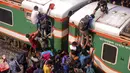 Ratusan orang berupaya menaiki atap kereta api untuk menuju kampung halaman di Dhaka, Bangladesh pada 4 Juni 2019. Pemadangan mencengangkan dari ratusan yang naik dan duduk di atas kereta karena gerbong yang penuh terlihat pada menjelang Idul Fitri di Bangladesh. (MUNIR UZ ZAMAN/AFP)
