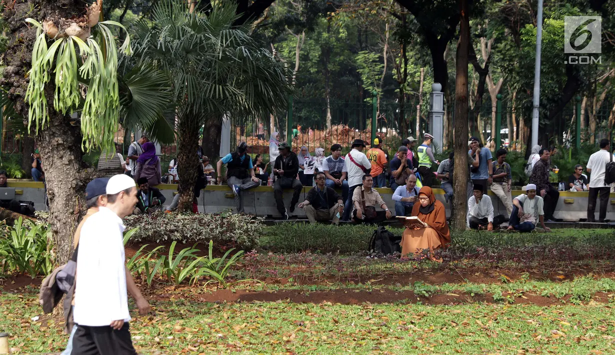 Salah satu peserta aksi membaca Al-Quran di taman pembatas Jalan Medan Merdeka Barat, Jakarta, Jumat (14/6/2019). Massa berkumpul menyampaikan pendapat terkait sidang perselisihan hasil pilpres 2019. (Liputan6.com/Helmi Fithriansyah)