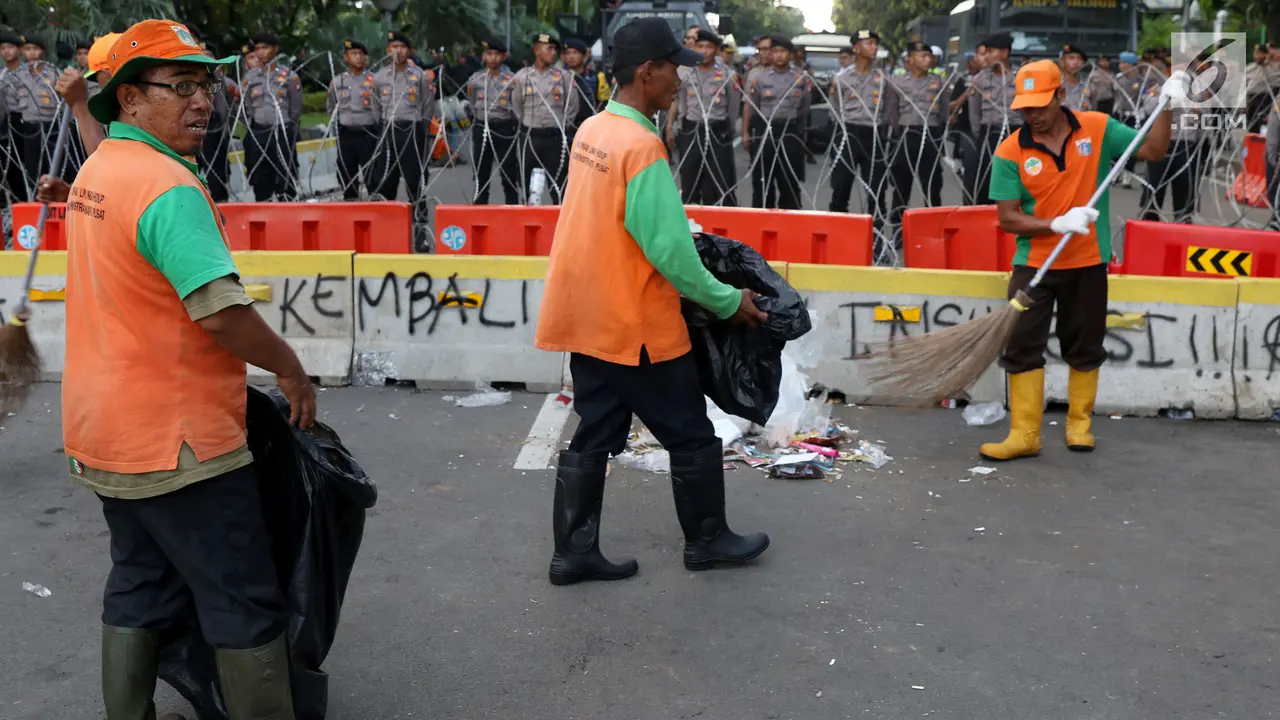Pasukan Oranye Berjibaku Bersihkan Sampah Sisa Aksi Buruh