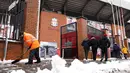Seorang petugas membersihkan salju di sekitar area Stadion Anfield menjelang laga lanjutan Liga Inggris 2024/2025 antara Liverpool melawan Manchester United pada Minggu (05/01/2025). (AFP/Darren Staples)