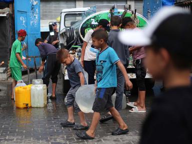Anak laki-laki Palestina membawa jeriken berisi air dari titik distribusi di kamp pengungsi Bureij, Jalur Gaza tengah pada 28 April 2025. (Eyad BABA/AFP)