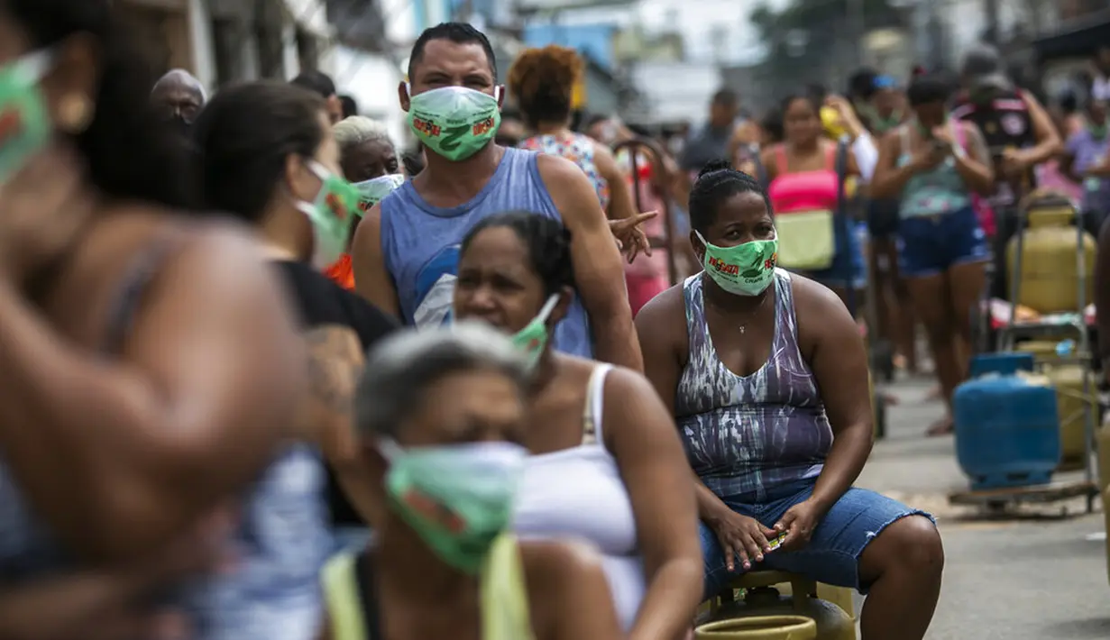 Warga memakai masker saat antre membeli gas murah dari Petrobrás Oil Tankers Union di favela Vila Vintem, Rio de Janeiro, Brasil, Jumat (12/3/2021). Kegiatan ini sebagai kampanye solidaritas untuk memperingati Hari Perjuangan Nasional Pertahanan Perusahaan Milik Negara. (AP Photo/Bruna Prado)