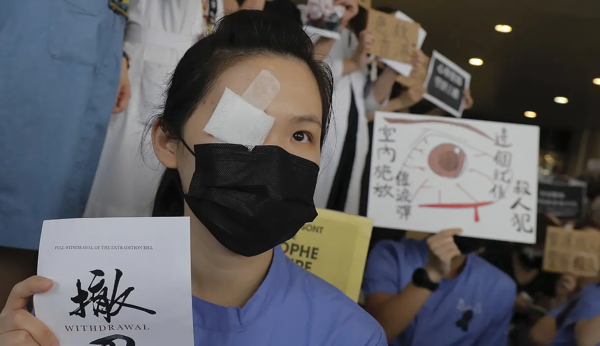 Seorang perawat mengenakan penutup mata dan masker mengambil bagian dalam protes terhadap kebrutalan polisi terhadap para pengunjuk rasa di sebuah rumah sakit di Hong Kong (13/8/2019). (AP Photo/Kin Cheung)