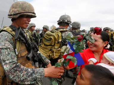 Tentara Filipina menerima bunga mawar merah usai bertempur di kota Marawi saat turun dari kapal amfibi Angkatan Laut Filipina BRP Tarlac di Manila, Filipina (30/10). Kota Marawi berhasil direbut dari para militan. (AP Photo / Bullit Marquez)