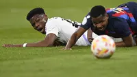 Bek Real Madrid, Aurelien Tchouameni (kiri) dan striker Barcelona, Ansu Fati terjatuh dalam perebutan bola pada laga leg pertama semifinal Copa del Rey 2022/2023 di Santiago Bernabeu Stadium, Madrid (2/3/2023). Aurelien Tchouameni baru memasuki musim pertama bersama Real Madrid sejak didatangkan pada awal musim 2022/2023. Musim ini ia telah tampil dalam 40 laga di semua ajang bareng Los Blancos dengan torehan 4 assist. (AFP/Oscar Del Pozo)