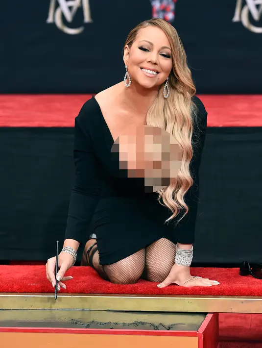 Penyanyi Mariah Carey menandatangani semen di TCL Chinese Theatre di Los Angeles, AS (1/11). Penyanyi 47 tahun ini mendapat penghargaan membuat cetakan tangan dan kaki di TCL Chinese Theatre. (Photo by Jordan Strauss/Invision/AP)