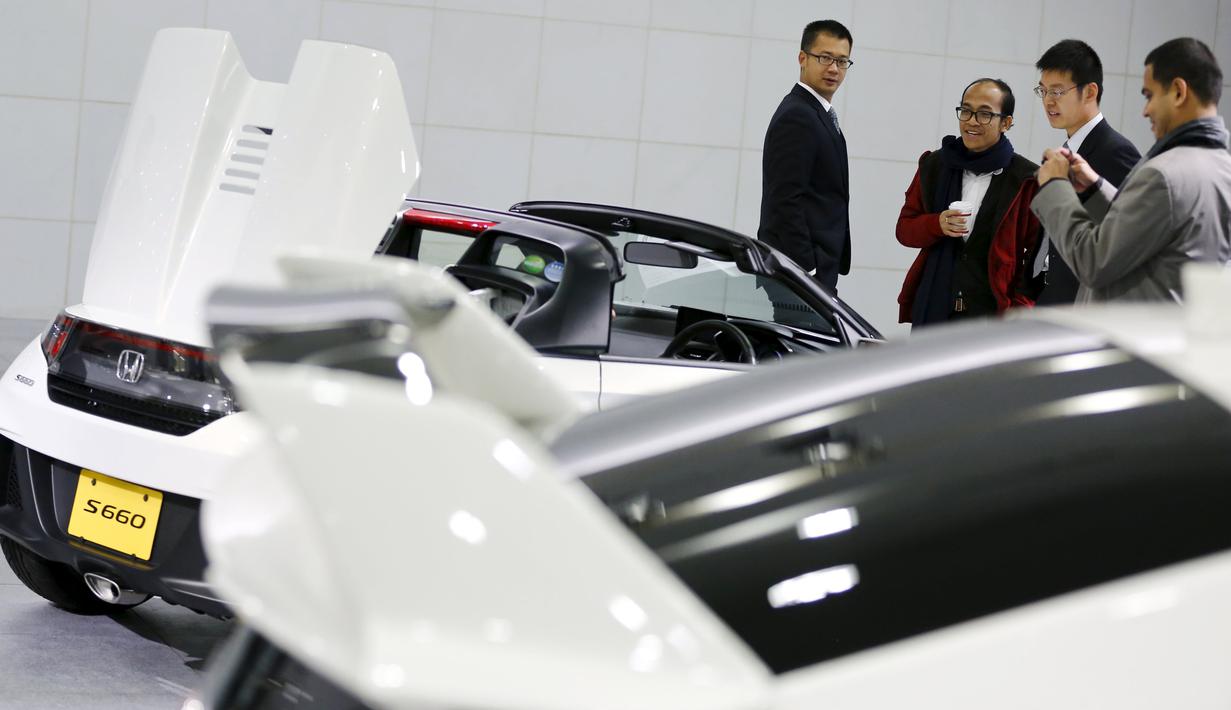Pengunjung terpesona melihat mobil Honda S660 di markas besar Honda Motor Co di Tokyo, Jepang, (24/2). Mobil Honda S660 adalah mobil sport yang memiliki dua tempat duduk berkatagori mobil yang sangat kecil. (REUTERS/Thomas Peter)